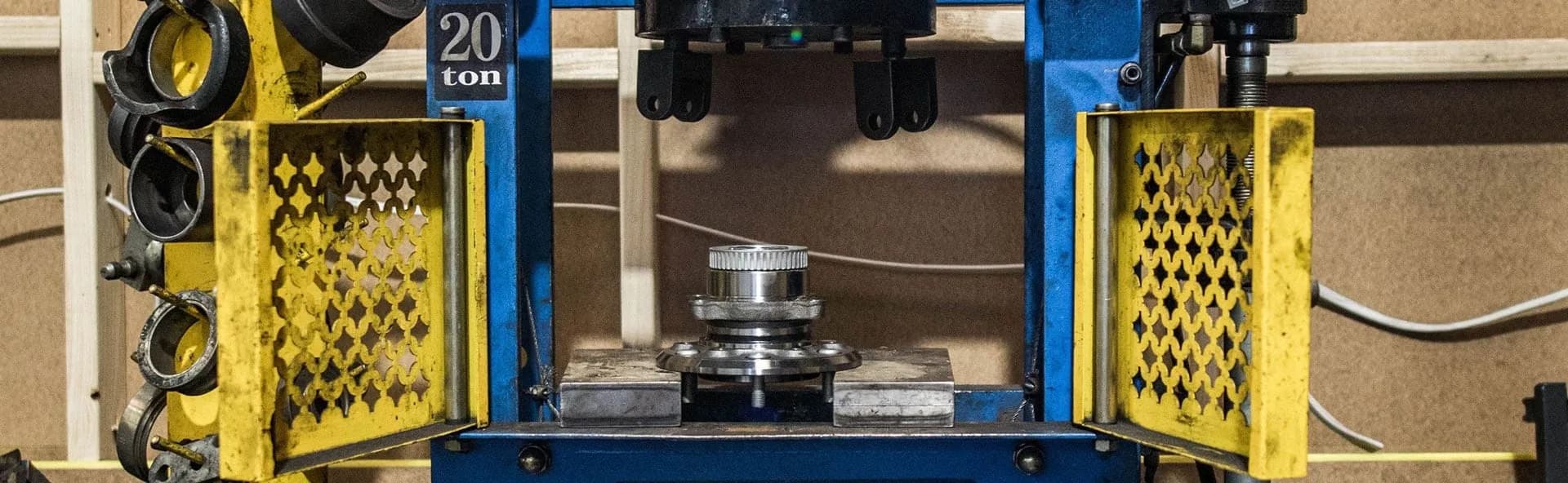 A workshop hydraulic press with yellow safety guards