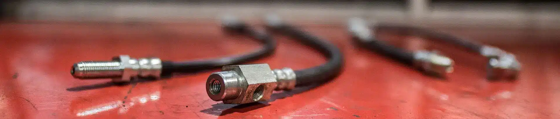 Brake hoses and metal connectors laid out on a red workbench