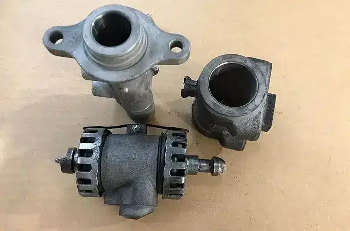 Three metal brake cylinder housings on a wooden work surface