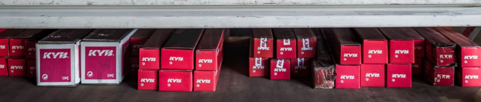 Rows of red KYB parts boxes on a shelf