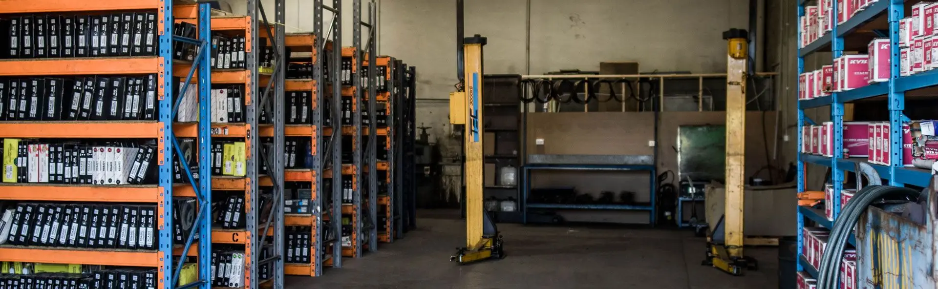 Workshop shelving stocked with boxed parts beside hydraulic presses